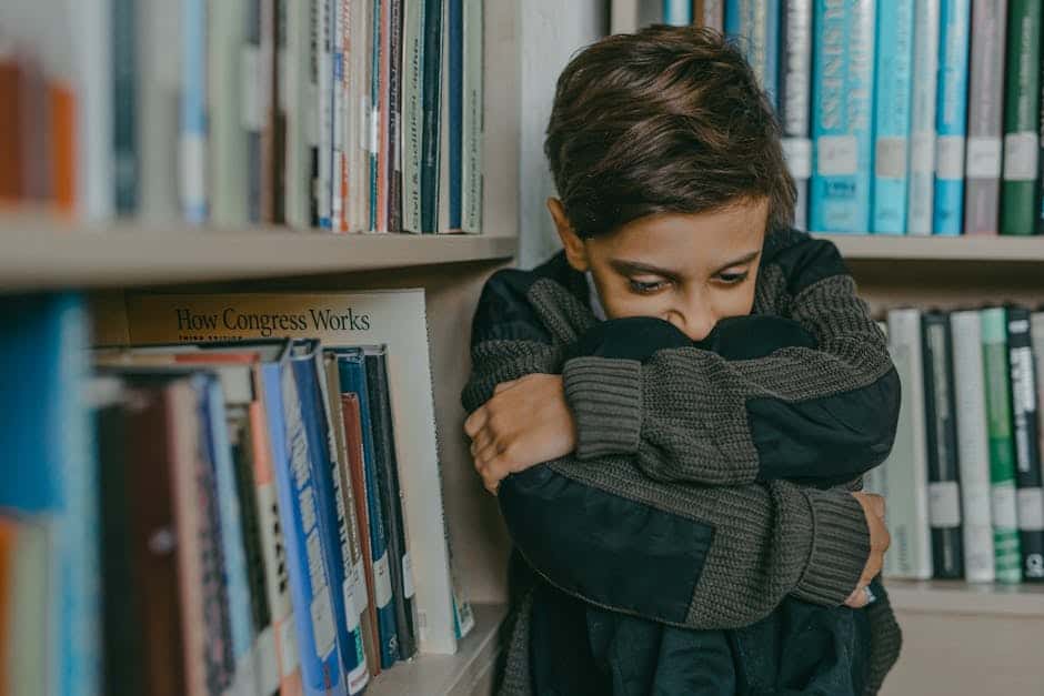 A young boy in a library reflecting amidst shelves of books, highlighting curiosity and introspection.