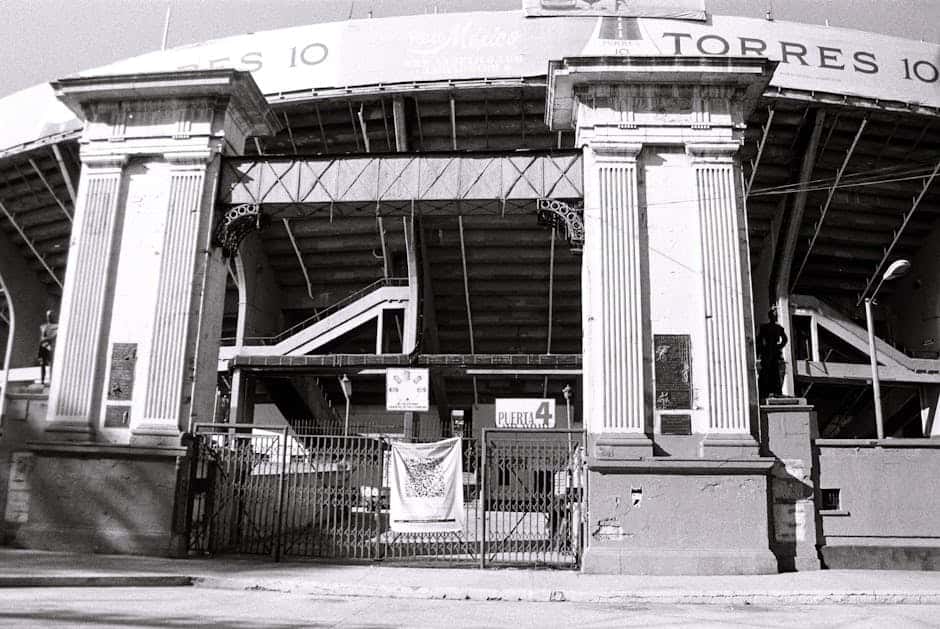 Black and white photograph of the iconic Estadio de Béisbol entrance in Mexico City, highlighting its architectural details.