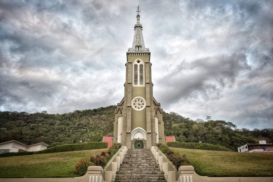 Beautiful Igreja Matriz Church in Santa Maria Madalena, Brazil surrounded by hills under a cloudy sky.