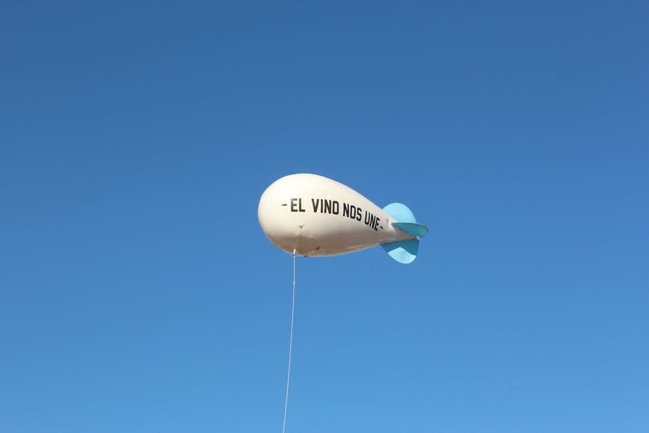A white balloon with 'El Vino Nos Une' phrase floats against a clear blue sky.