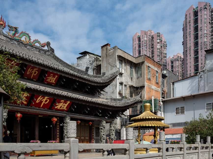 A blend of historical and modern architecture in Guangzhou, China, featuring a traditional temple and high-rise buildings.
